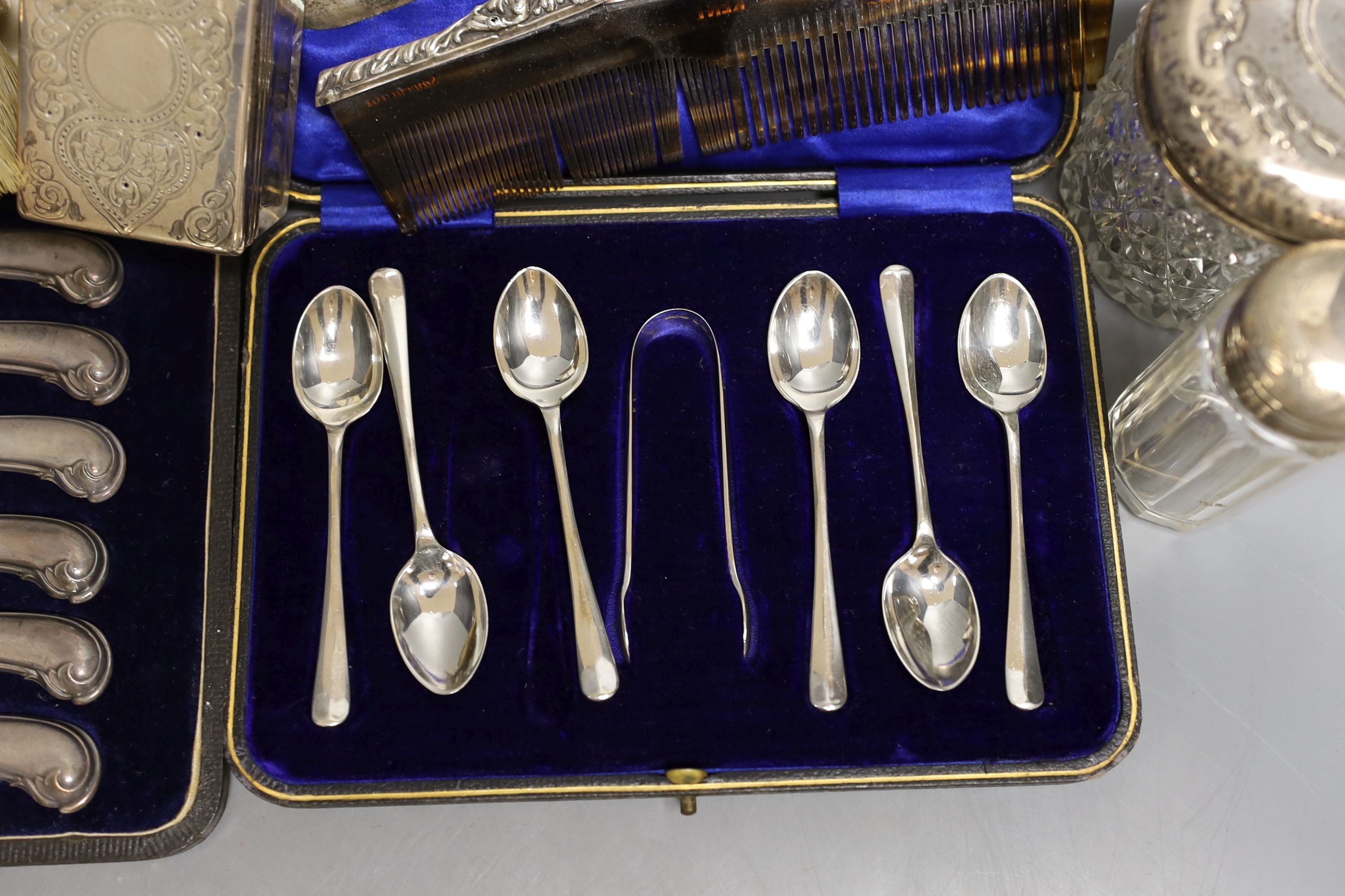 Four assorted silver mounted glass toilet jars, a silver mounted brush, two combs and a shoe horn and two cased sets of cutlery including silver teaspoons with tongs.